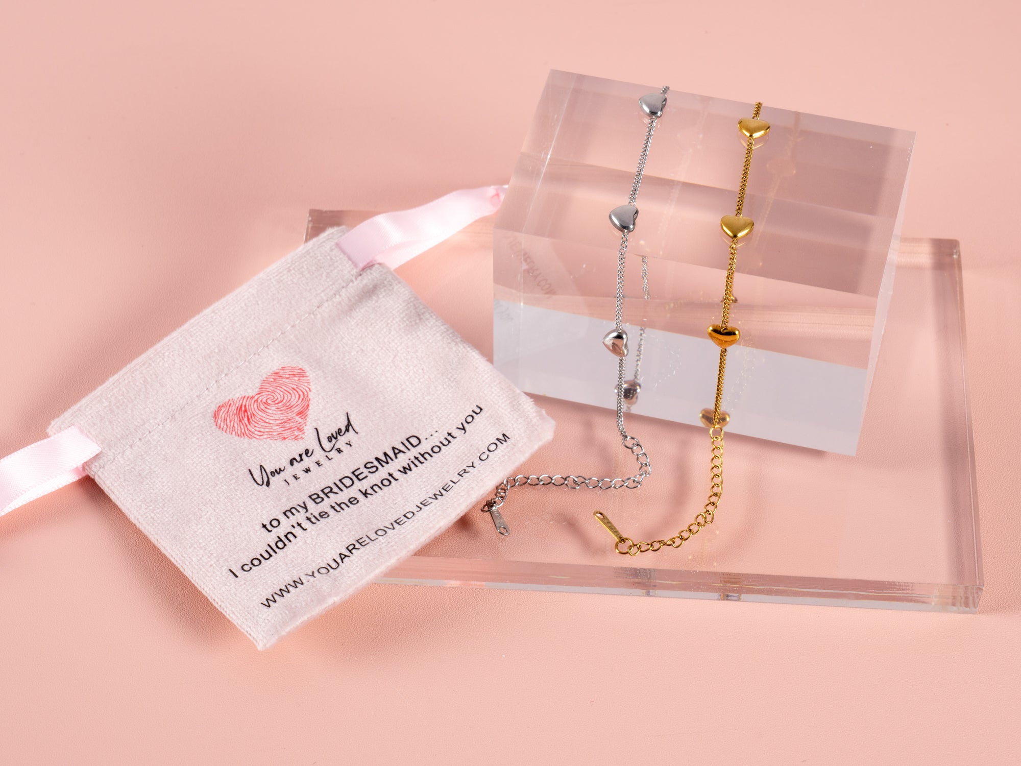 multi heart gift bracelets shown here on a clear cube and a pink bridesmaid can't tie the knot without you gift pouch next to it. These are great gift bracelets for all your bridesmaids