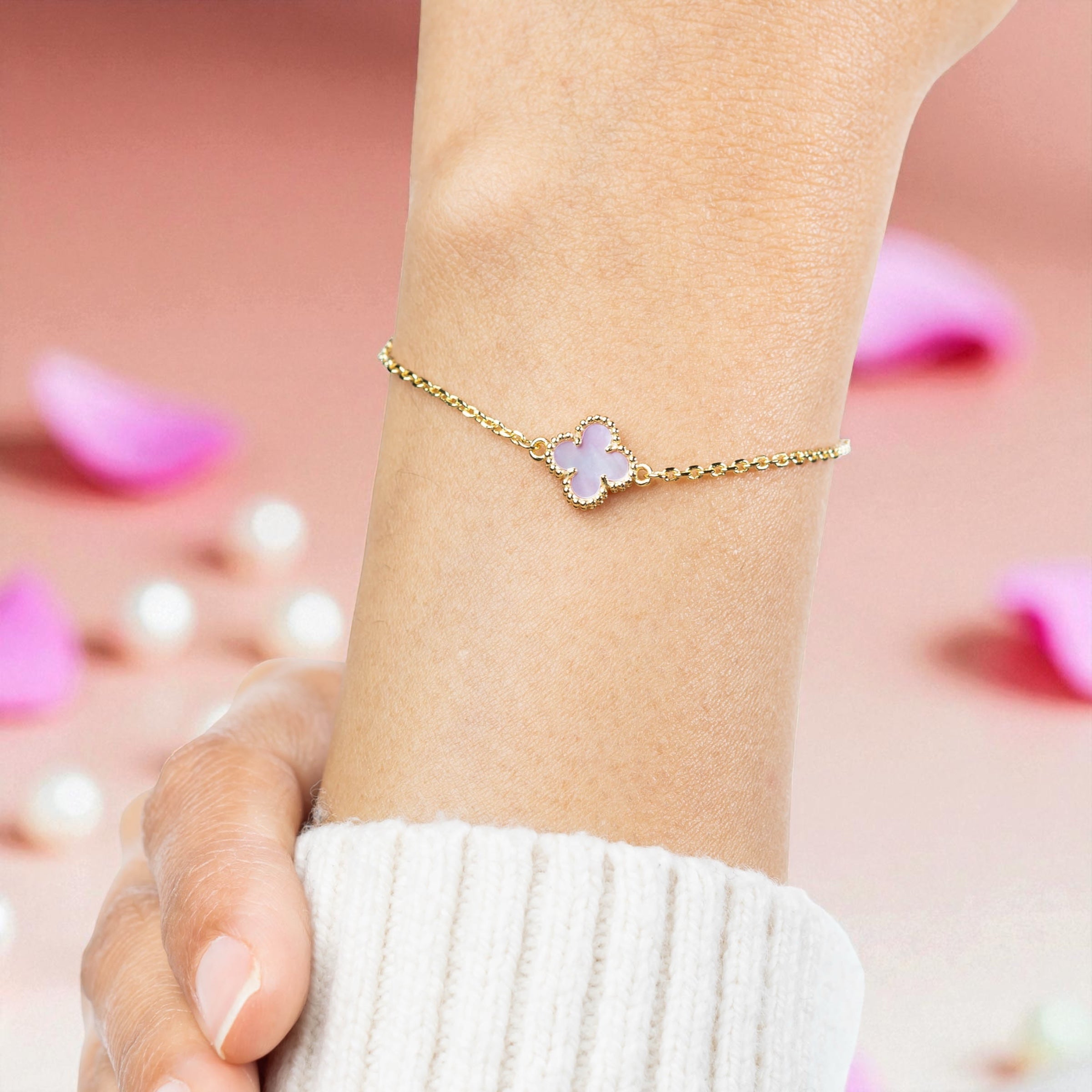 pink four leaf clover charm bracelet on a wrist and can be given to bridesmaids in their proposal gift boxes