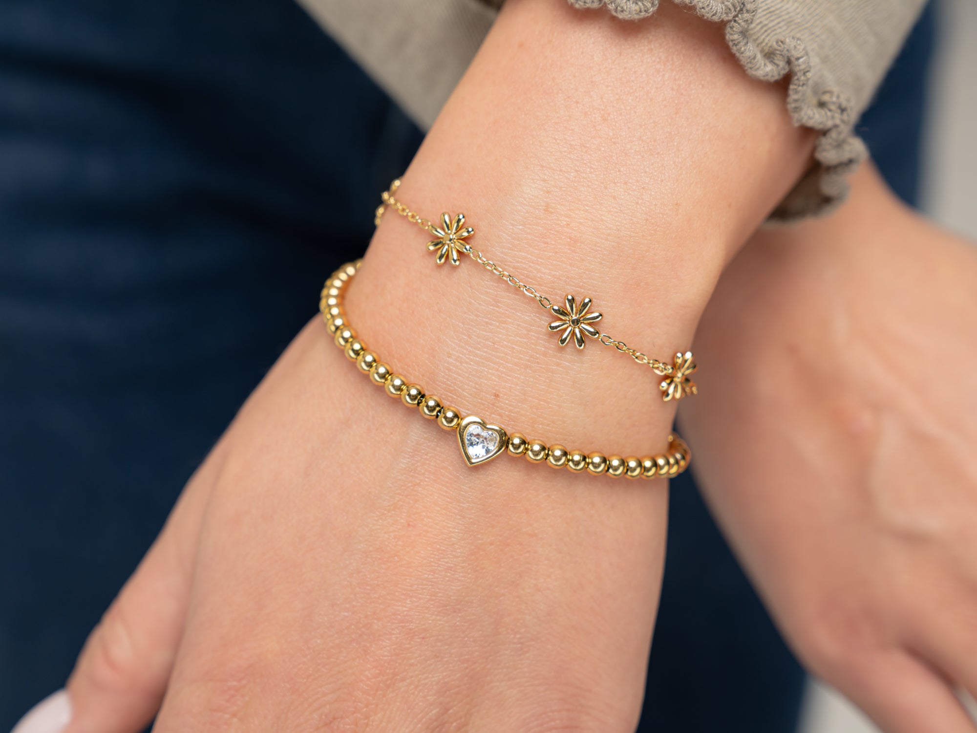 heart gemstone 8k gold plated bracelet and a flower bracelet shown here on a wrist these bracelets can be perfect bridesmaid gift jewelry