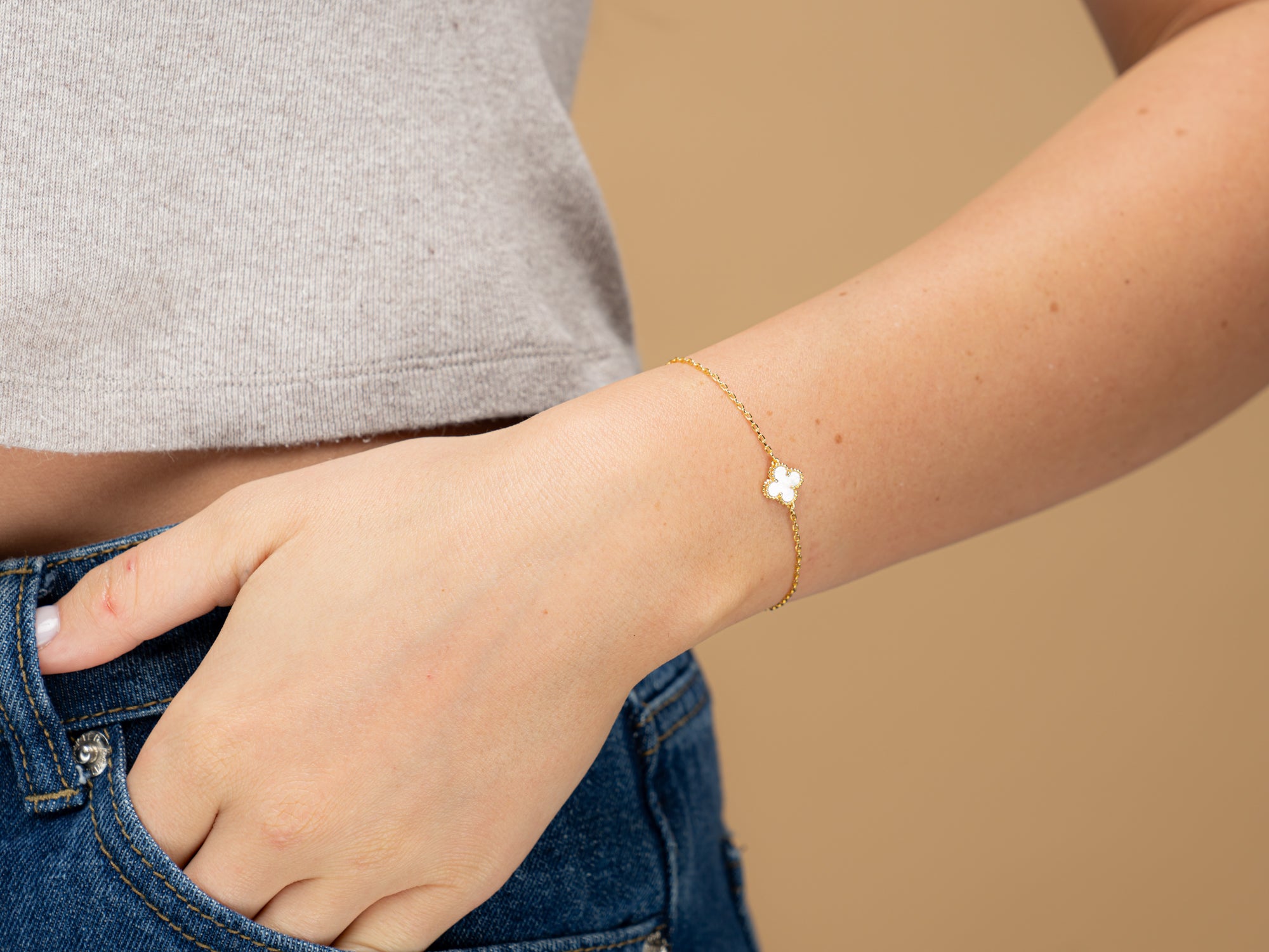 white clover bracelet shown on a wrist this bracelet has a lucky charm white four leaf clover on it